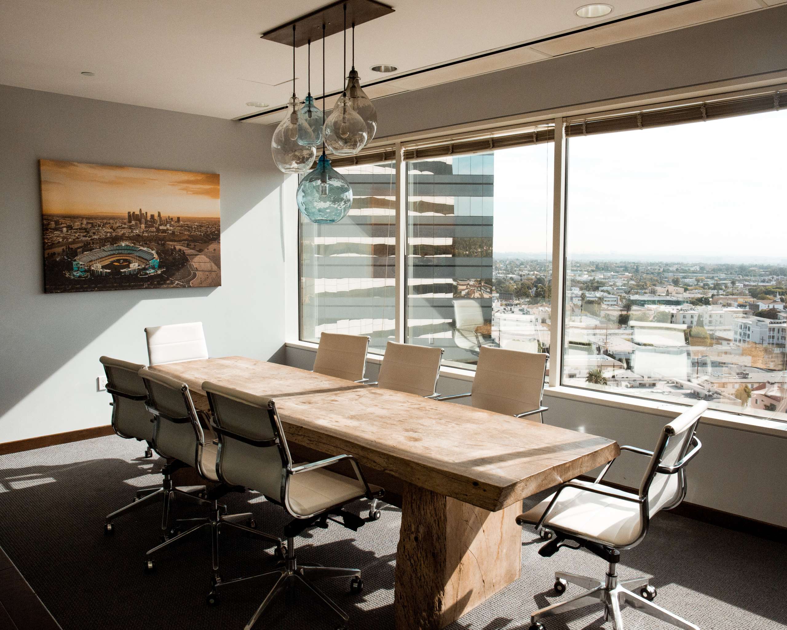 An office with a sleek wooden table and modern chairs, illuminated by a stylish pendant light hanging above the table.